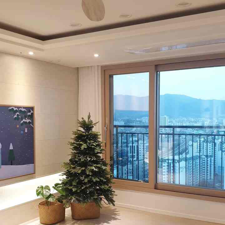 A beige and natural tone living room featuring a large window and Christmas tree in a clean, modern space