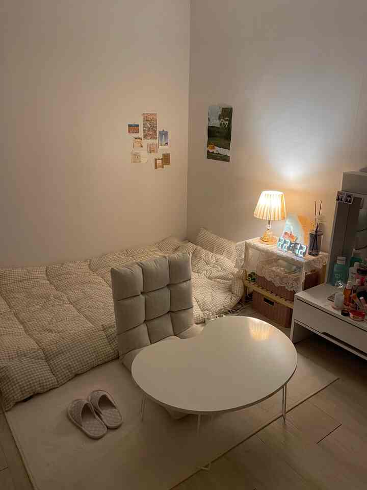 白とベージュのトーンでまとめられた6坪のワンルーム寝室、座椅子と小さなナイトテーブルが配置された印象的な空間