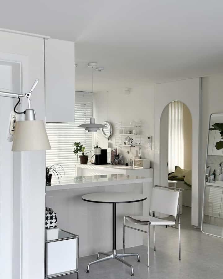 White-toned living room and kitchen featuring an arch-shaped partition and modern furniture in a clean interior
