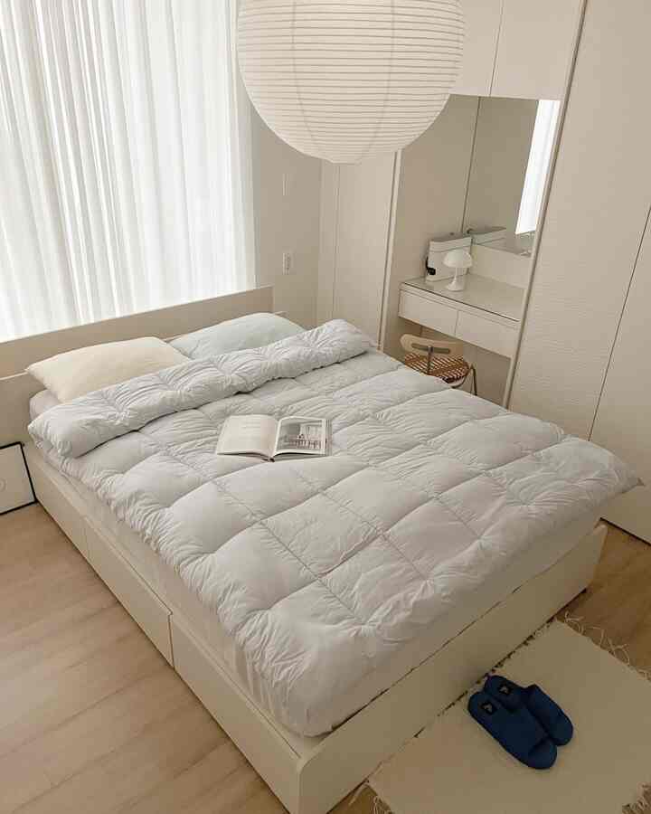 Soft white-toned bedroom featuring a large bed with cozy duvet cover centrally placed