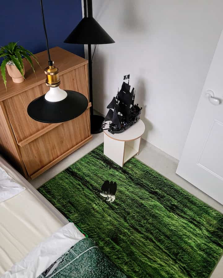 Room with white walls and wood tone furniture featuring a green rug, side table, and modern lighting in mid-century modern style