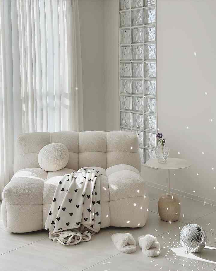 ホワイトとアイボリーの色調のリビング、ふわふわのソファとスロー、ミラーボールが調和した居心地のよいモダンな北欧インテリア