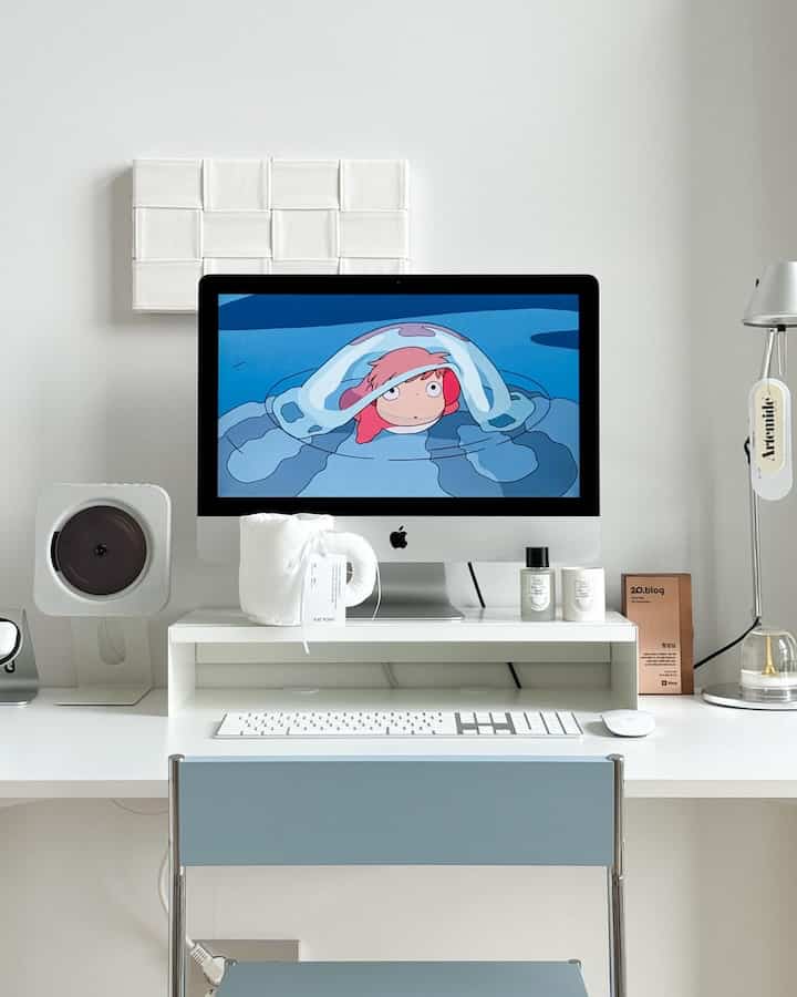 白と青のトーンが特徴的なミニマルなホームオフィス、アップルのアイマックと整然としたデスクが配置された作業空間
