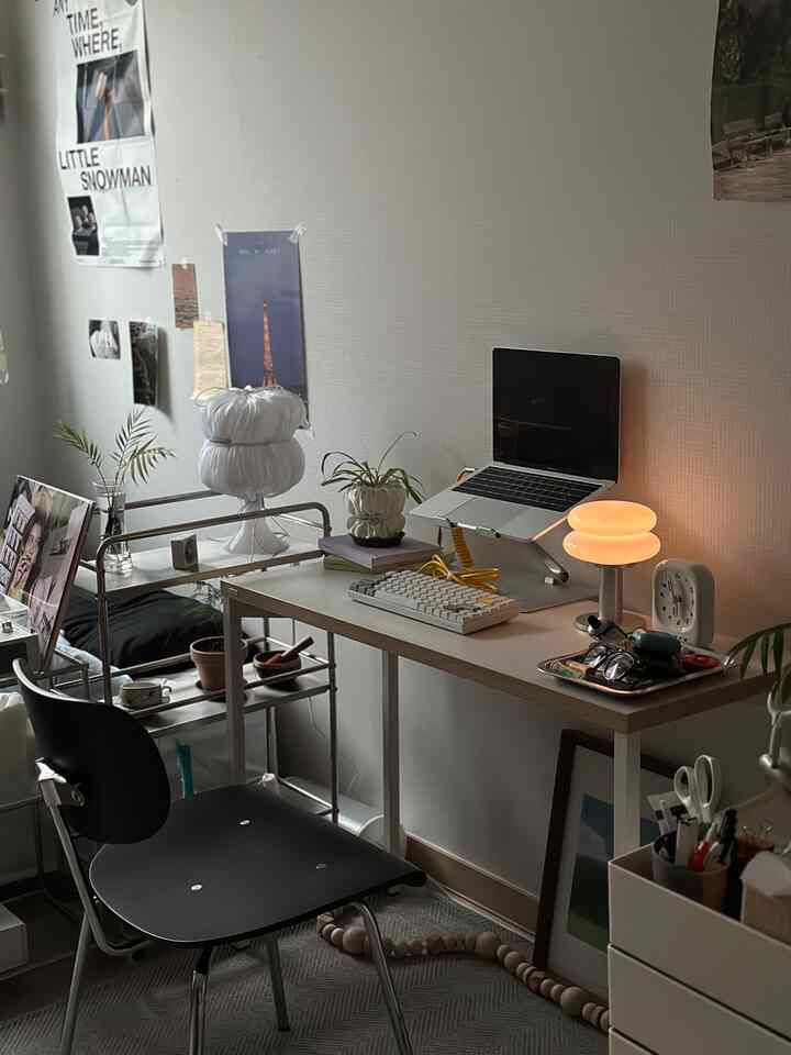 白を基調としたワンルームのホームオフィス、ミッドセンチュリーモダンスタイルのデスクと黒いオフィスチェアが配置された雰囲気のある作業空間