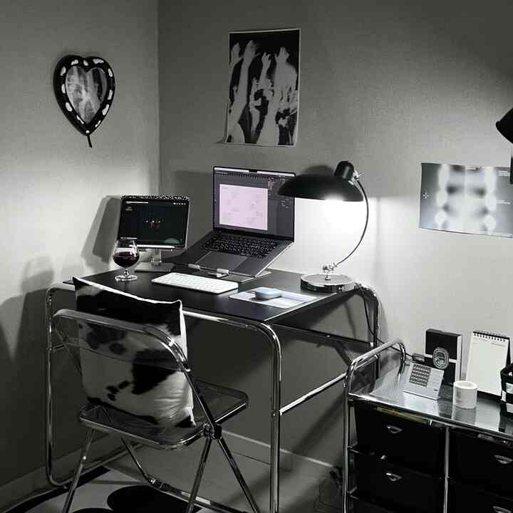 ブラックとホワイトのモノトーン調、ミッドセンチュリーモダンのホームオフィス。クロームフレームのデスクと折りたたみ椅子が配置された雰囲気のある空間