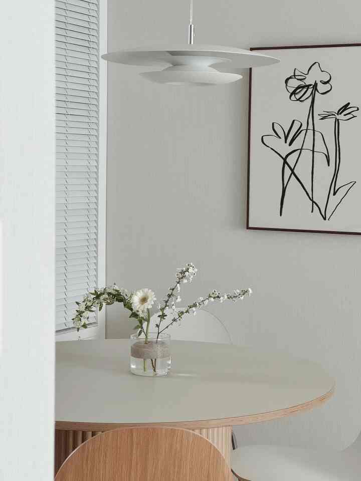 明るいホワイトトーンのダイニング、木製のテーブルと透明なガラスの花瓶が調和したミニマルでナチュラルなインテリア