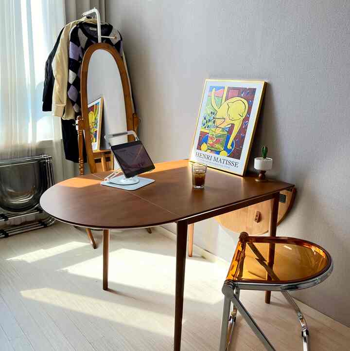 ナチュラルモダン調の狭い部屋、木製折りたたみダイニングテーブルとミッドセンチュリーモダンチェア、額縁と姿見が調和した雰囲気のあるインテリア