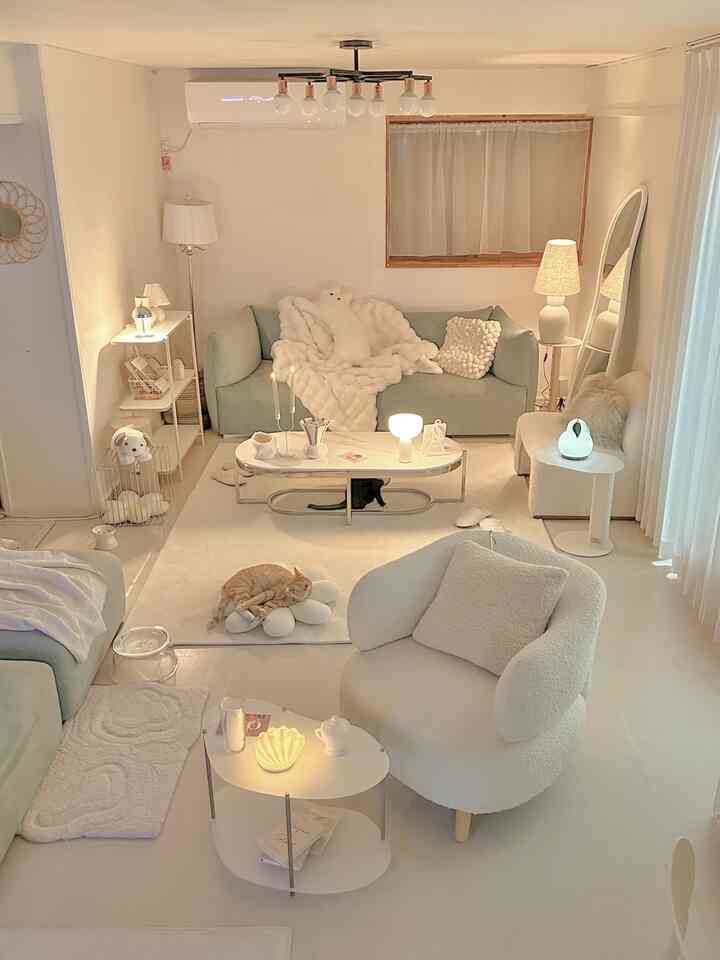 Warm natural modern living room featuring mint sofa, armchair, coffee tables, and cats resting comfortably in a cozy space