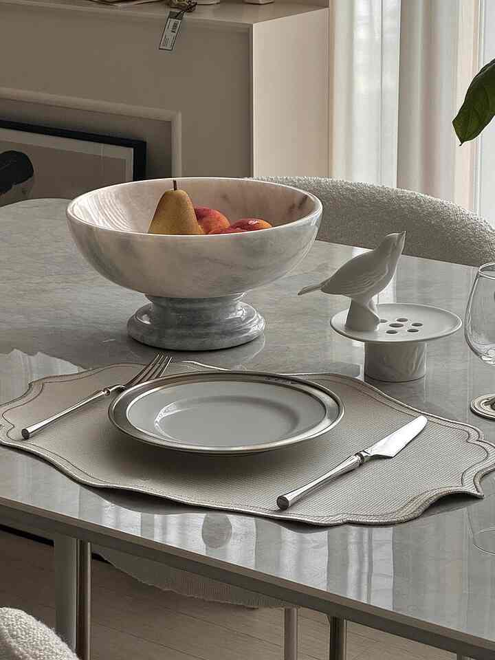 白とグレーのトーンのダイニング、マーブルのダイニングテーブルとファブリックのダイニングチェアが配置された洗練された空間