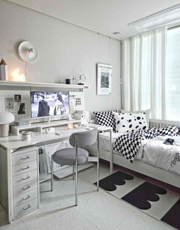 White-toned kids' room featuring monochrome checkered and spotted pillows and bedding with a clean, modern interior style