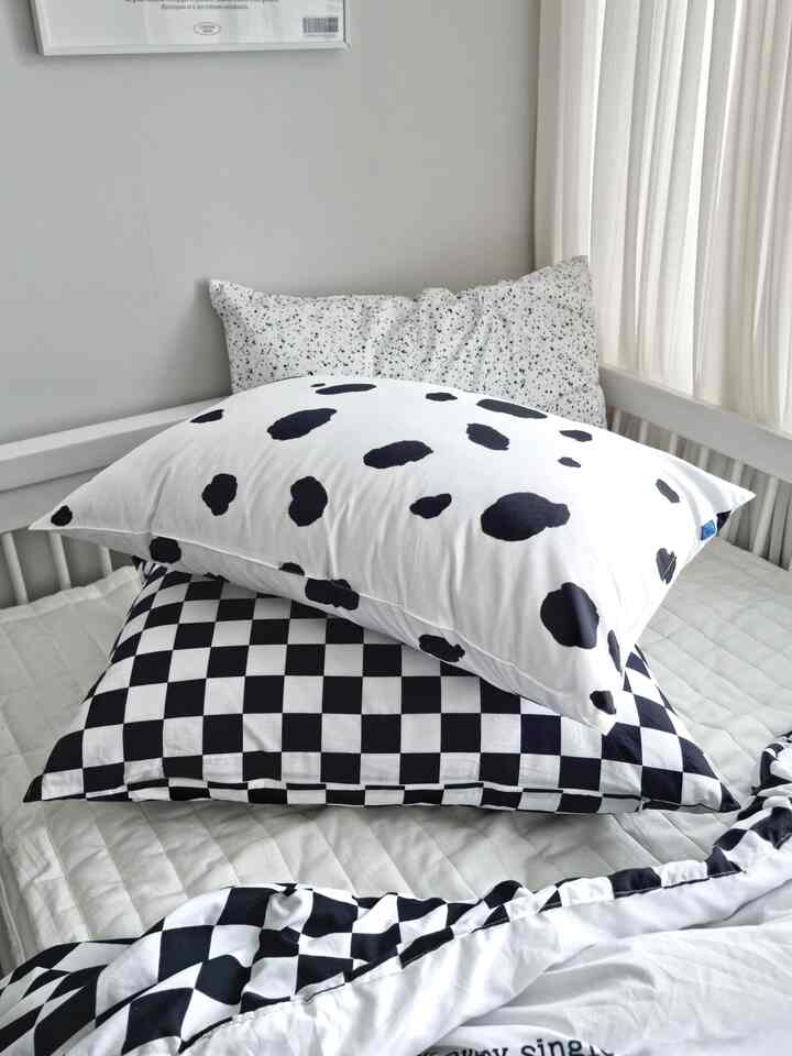Bright kids' room bedroom featuring white and black patterned pillow covers and duvet cover with a white bed frame