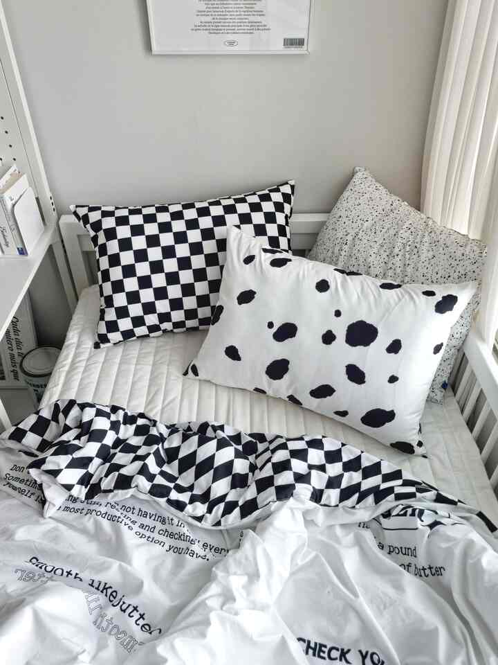A white and black-toned kids' bedroom featuring a Mid-Century Modern styled neat bed with checkered and spotted pillows
