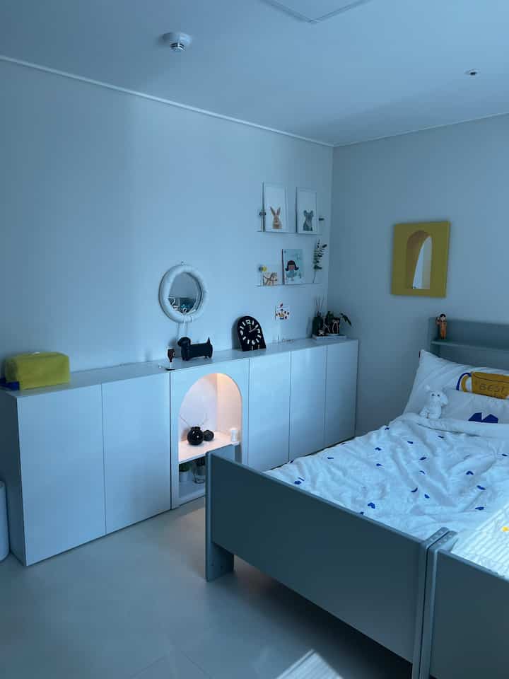 白と青のトーンの子供部屋、子供用ベッドと収納キャビネットが配置されたシンプルな空間