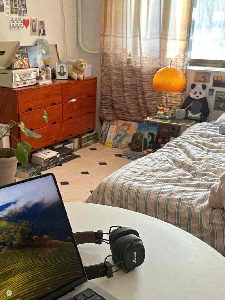 暖かいベージュ色のカーテンと木製チェストが配されたナチュラルでヴィンテージ感のある落ち着いた寝室