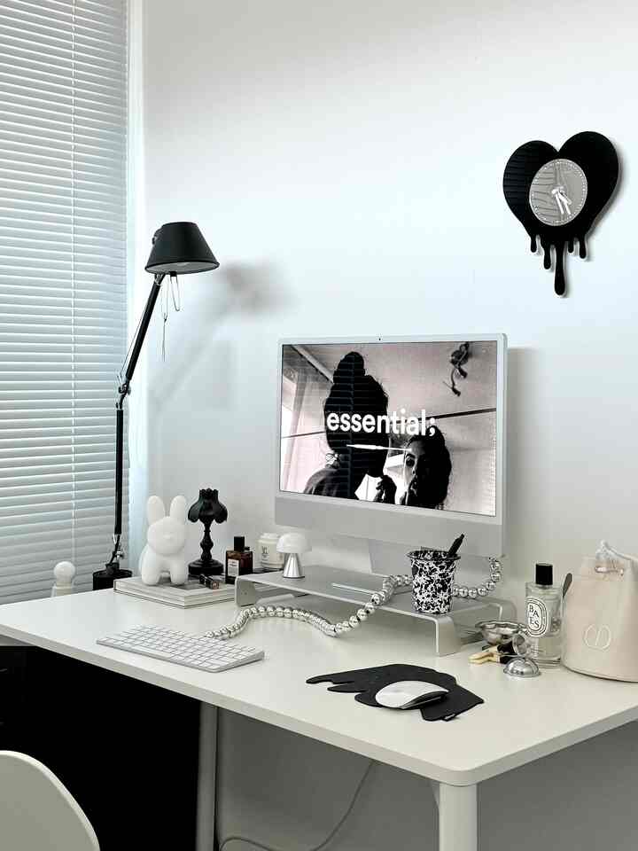 Monotone black and white study featuring a white desk, computer, and black desk lamp creating a clean workspace