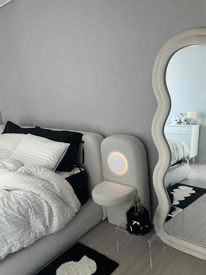 白を基調とした寝室、丸いライトと波形の全身鏡が配置されたモダンなインテリア