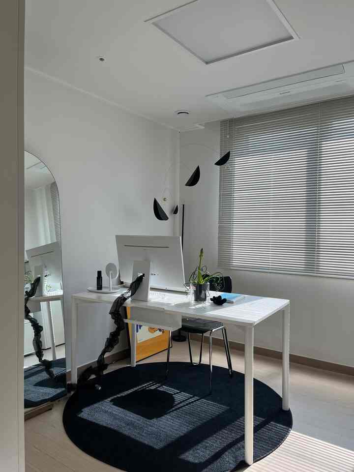 Modern home office space in white and black tones featuring a white desk and black chair with minimalist décor