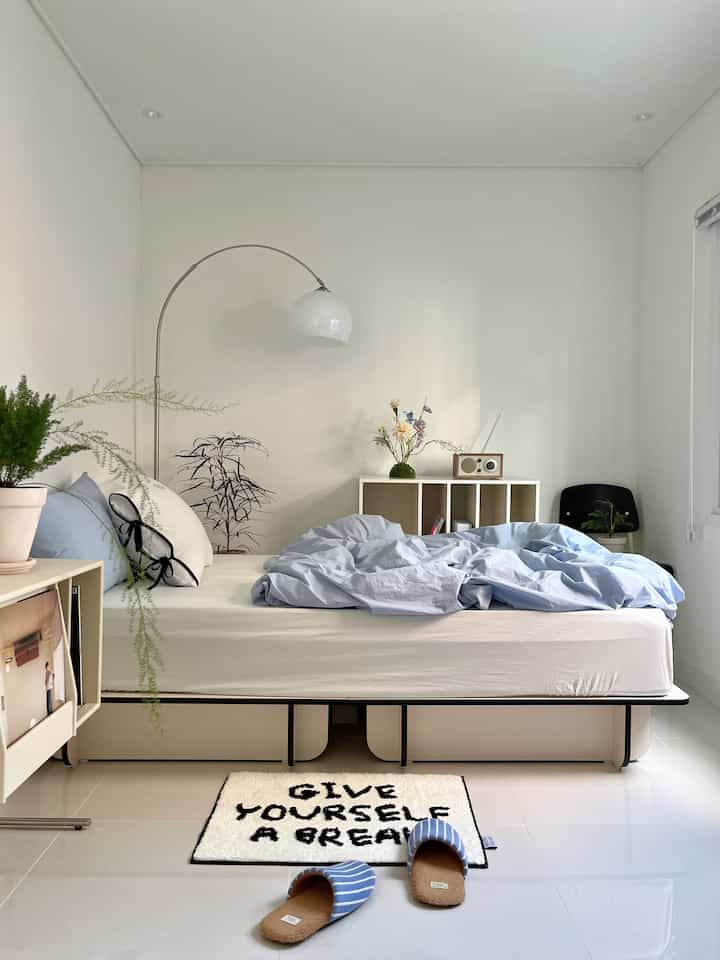 White-toned bedroom featuring blue bedding centrally placed, creating a neat and natural atmosphere