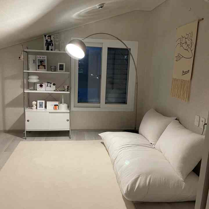 白とシルバーの色調のロフト、モダンで落ち着いた雰囲気の中に大きなフロアランプとソファ、棚が配置された印象的な空間