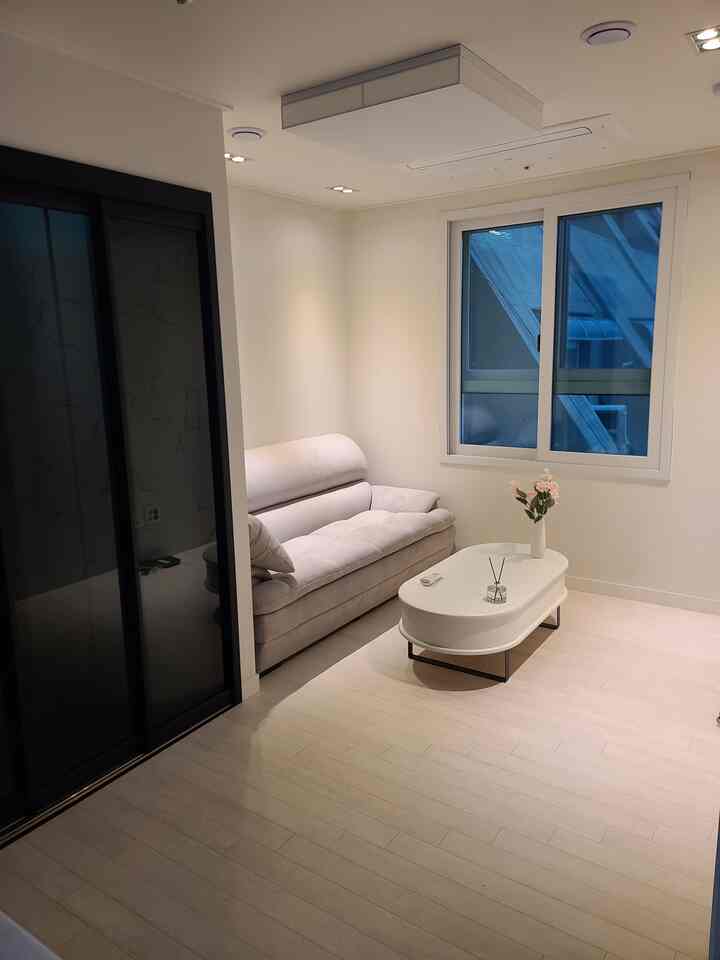 明るいベージュのソファと白いコーヒーテーブルが配置されたシンプルでナチュラルなリビングルーム