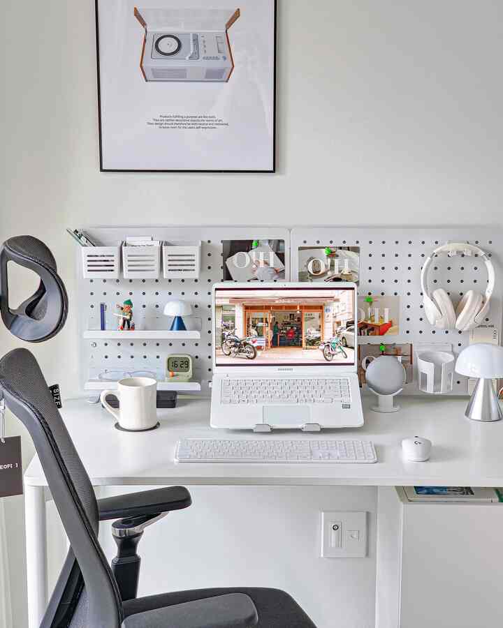 White and gray toned home office space featuring a white desk with a laptop and lamps, creating a simple and clean workspace