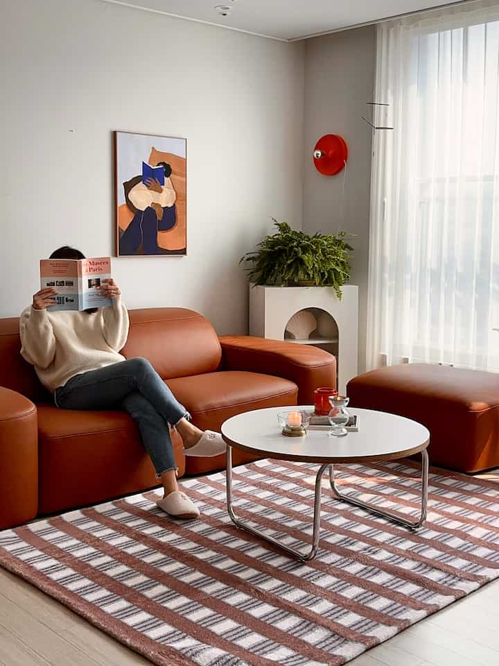 Modern living room with warm brown leather sofa and white round coffee table, featuring soft natural light and minimal decor for a cozy atmosphere