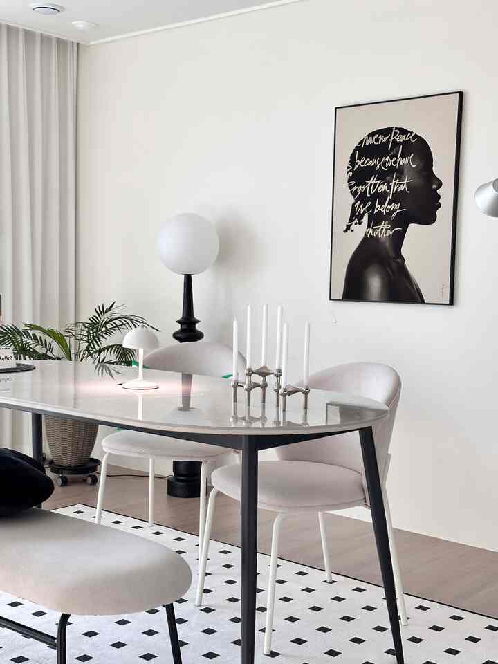 White and black toned dining room featuring an oval dining table, chairs, candle holder, and floor lamp in a modern setting