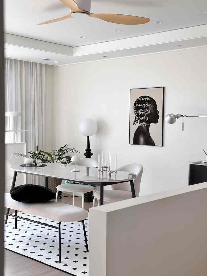 白とグレーのトーンで統一されたモダンなダイニング、光沢のあるセラミックダイニングテーブルとベンチ、椅子が配置された印象的な空間