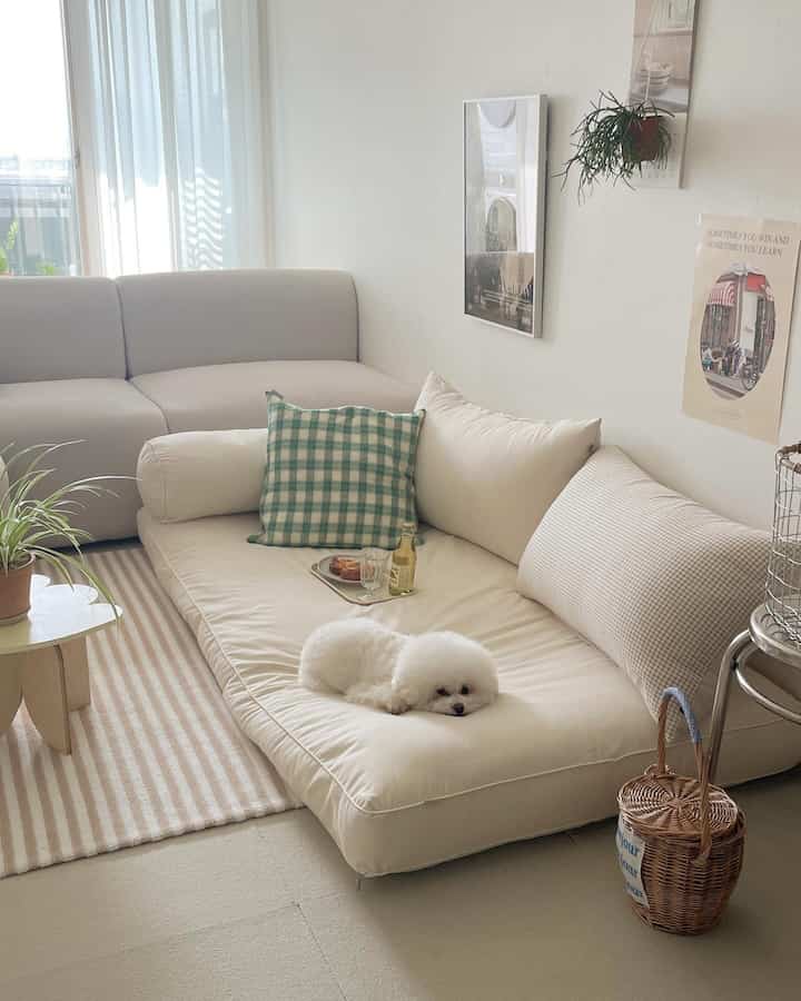 白とグレーのトーンのコンパクトなリビング、床座りのソファと大きな座布団、クッションが配置された雰囲気のあるインテリア