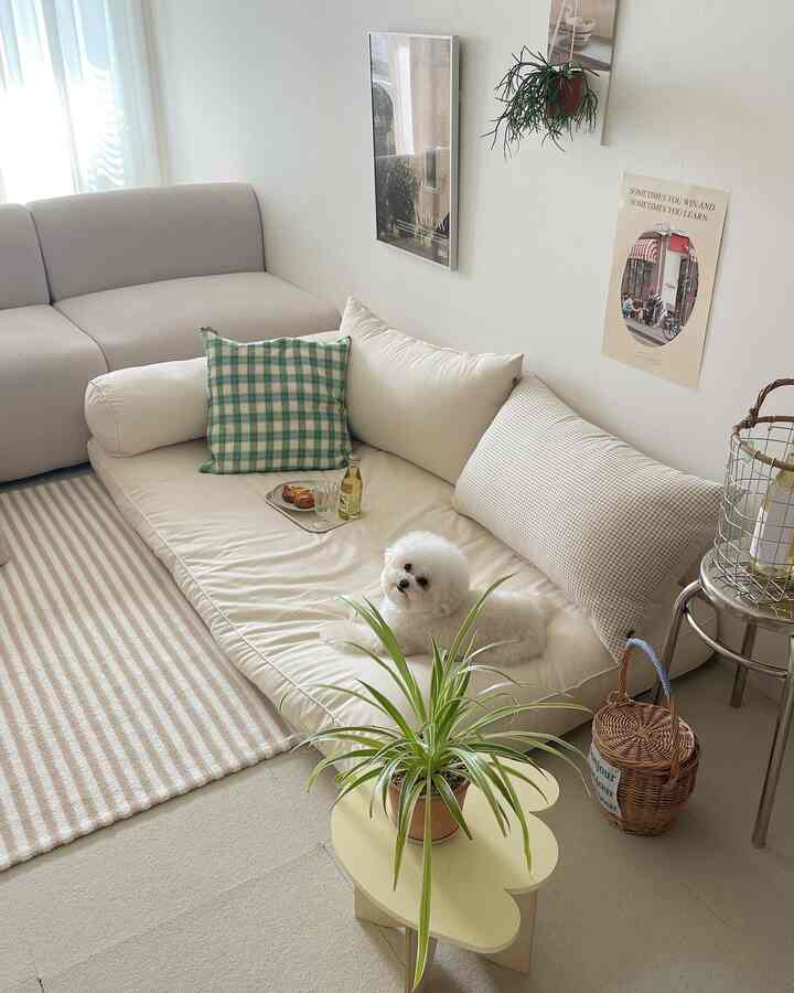 ベージュとホワイトのトーンのリビング、広いクッションとソファ、犬と植物が配置されたシンプルでナチュラルな印象的な空間