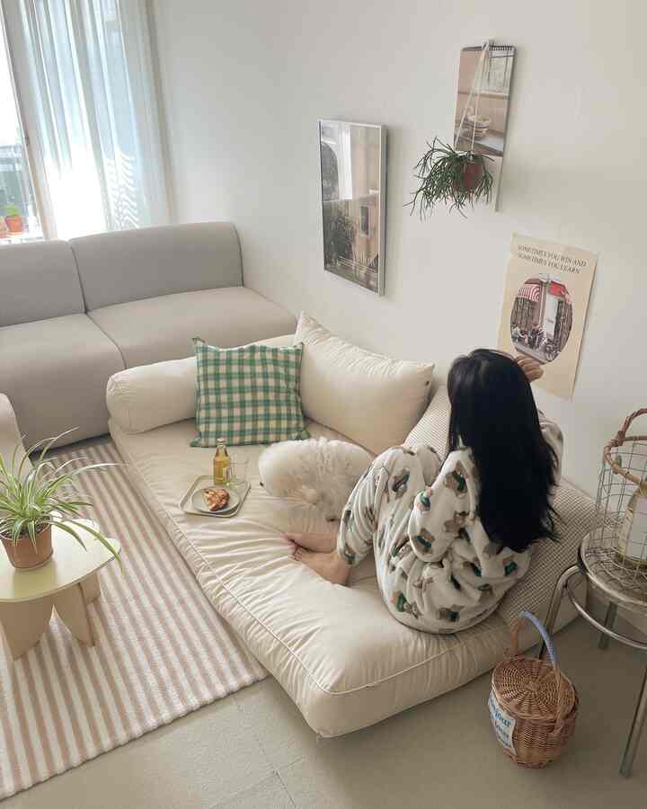 明るい白とグレーのトーンのリビング、ソファとラグが配置され、小さな犬と人がくつろいでいる印象的な空間