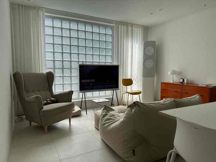 ホワイトとベージュの縦長リビング、ビーズクッションソファとアームチェア、赤いチェストが調和するモダンな雰囲気のインテリア