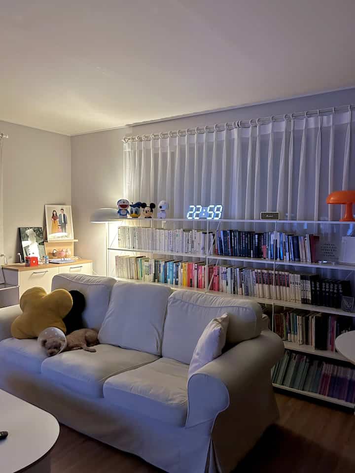 White-toned living room featuring a large sofa and bookshelf with a calm and cozy atmosphere