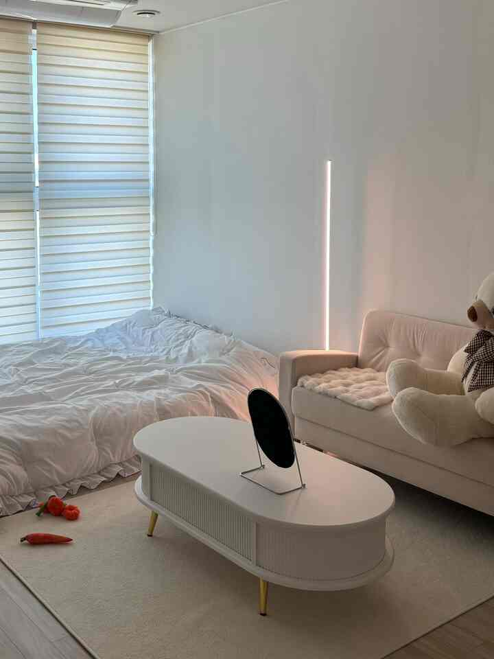 白とナチュラルカラーの寝室、ソファとコーヒーテーブルが配置されたシンプルで落ち着いたインテリア