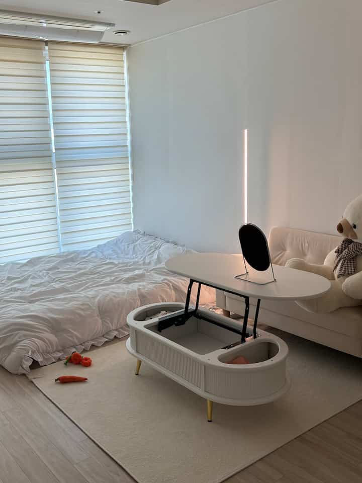 白を基調としたワンルームのリビング、アイボリーのソファが配置されたシンプルで自然な雰囲気の空間