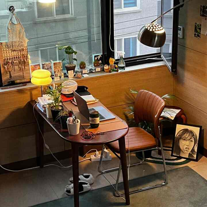 温かみのあるブラウンとシルバーのホームオフィス、デスクにノートパソコンと植物が配置された雰囲気ある作業空間