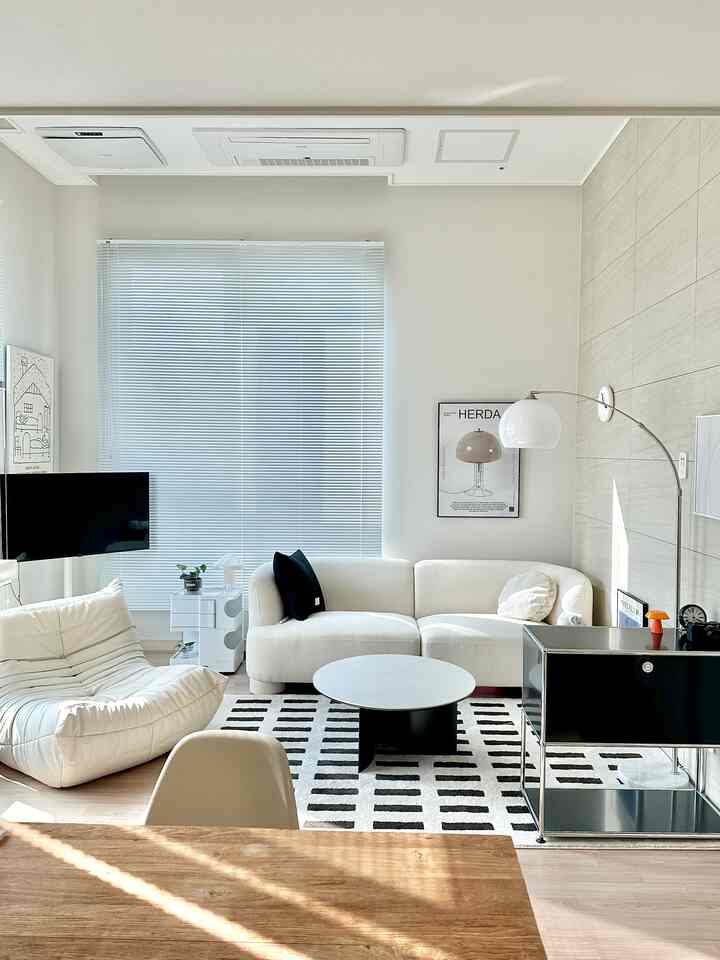 ホワイトとブラックのモノトーンリビング、コーナーソファとパターンラグが配置されたモダンで清潔感のある印象的な空間