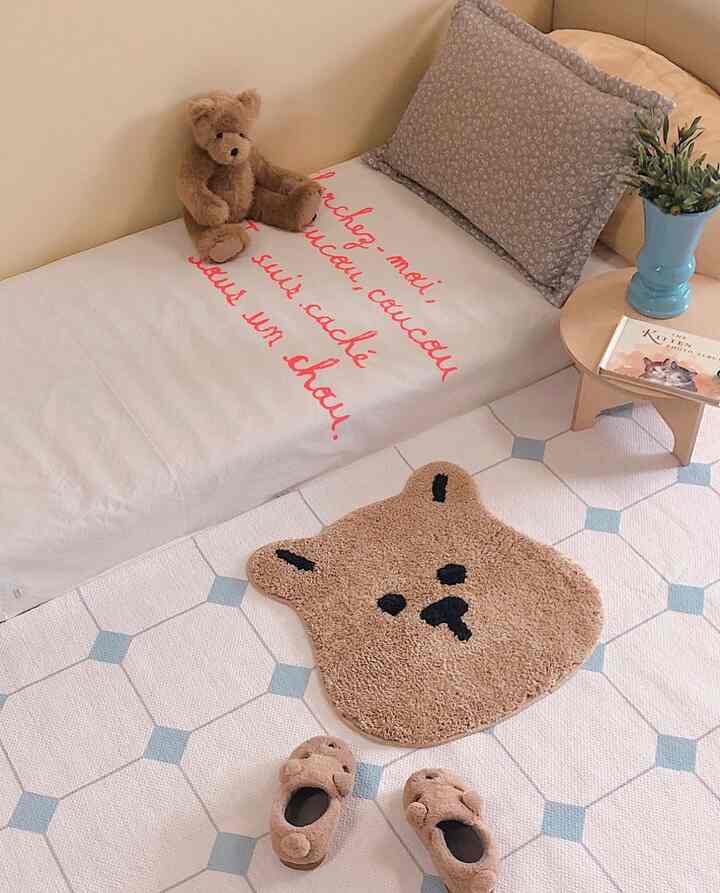 柔らかなベージュとブラウンの色調の寝室、テディベアとクマの形のラグが居心地の良い雰囲気を作り出している空間