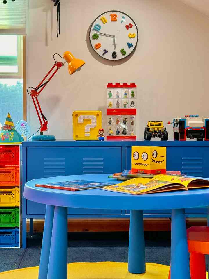 Bright blue and yellow toned kids' room featuring a round kids' table with various toys, creating a lively space