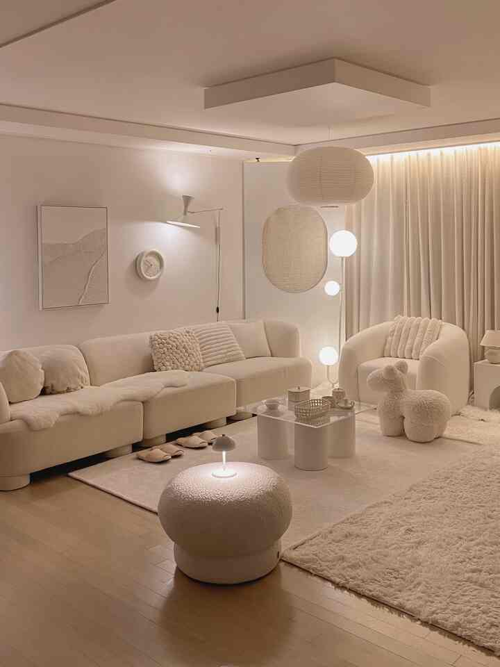 クリームアイボリーとホワイトの色調のリビング、モジュラーソファとブークレラグが配置された落ち着いた雰囲気の空間