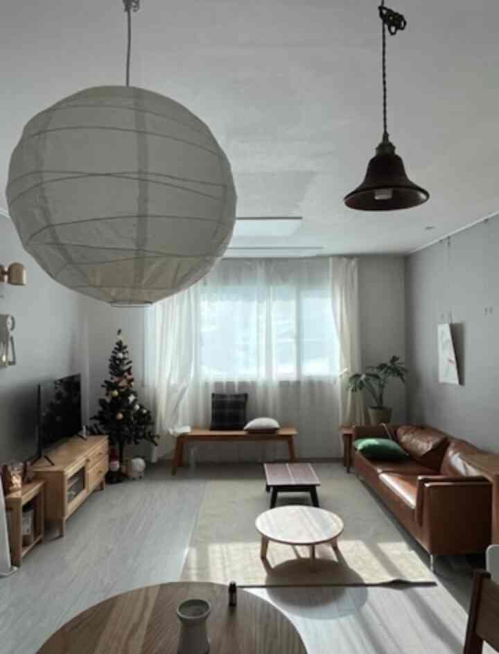 明るい白とナチュラルな木目調のリビング、ブラウンの革ソファと木製テーブルが配置された落ち着いた空間