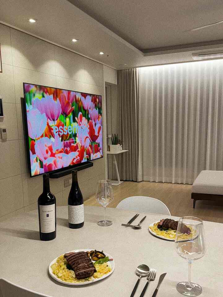 白とベージュの色調のダイニングルーム、ステーキとワイングラスが配置されたモダンで落ち着いた空間