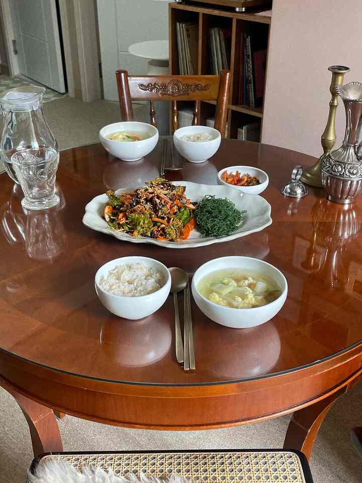 温かみのあるブラウン調のクラシックなダイニングルーム、木製のダイニングテーブルと椅子に韓国の食器が配置され、落ち着いた雰囲気のインテリア