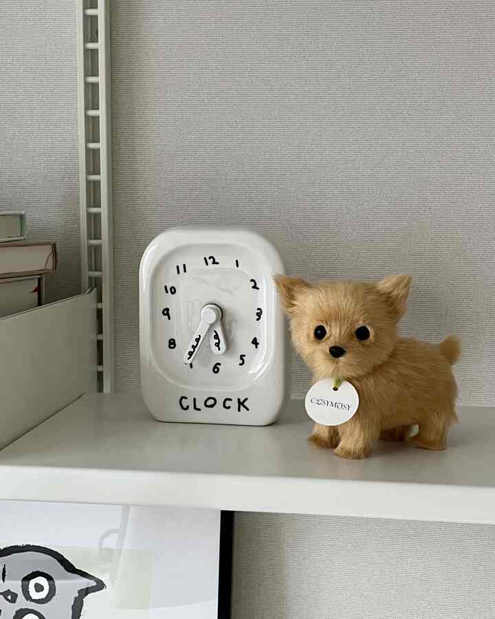 White-toned shelf featuring a clock and a dog-shaped plush toy creating a cozy decor space