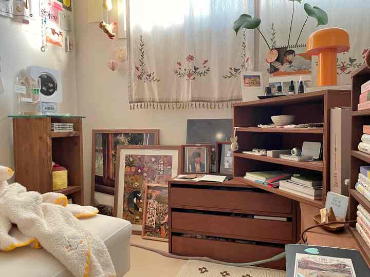 ベージュ調のナチュラルカラーの赤ちゃん部屋、木製家具と多彩な額縁が配置された温かみのある雰囲気のインテリア