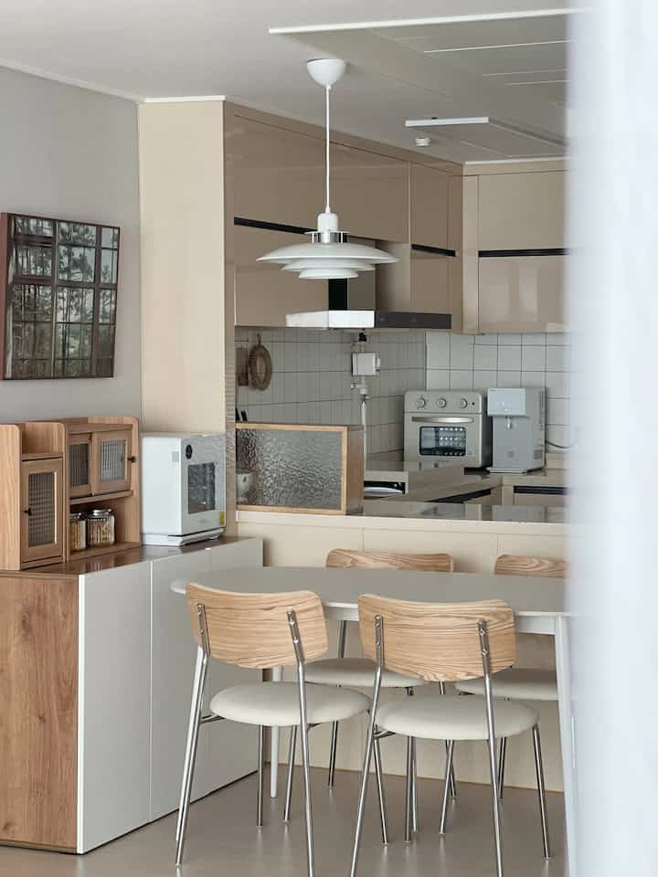Bright white and beige kitchen featuring wooden dining chairs with a clean and cozy natural aesthetic