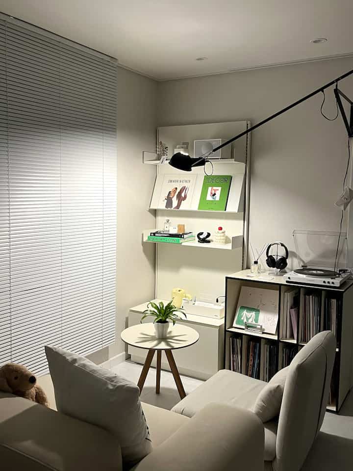 ホワイトとナチュラルトーンのリビング、棚とターンテーブル、植物が配置されたヴィンテージ感のある音楽空間