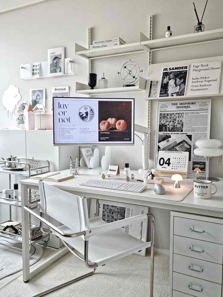 White tone study featuring a mid-century modern armchair and monitor arm in a clean home office setup
