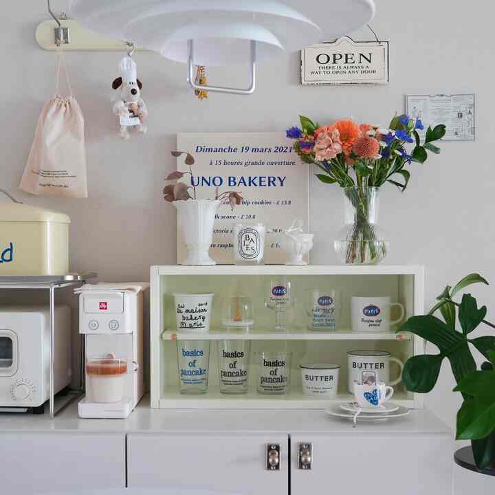 柔らかな白と木目調が調和するキッチン空間、コーヒー用品と花瓶が配置された雰囲気のあるおうちカフェゾーン