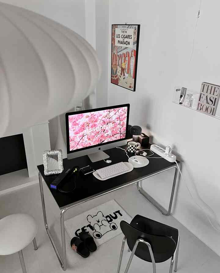 白い壁と床に、黒いデスクとチェアが配置された、モダンでミニマルな一人暮らしのホームオフィス